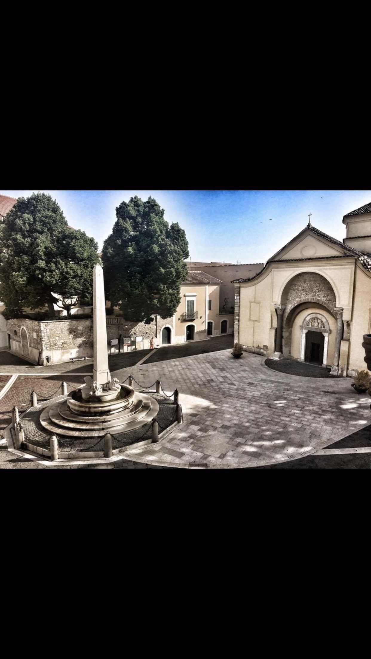 A courtyard with a central monument, surrounded by buildings with classical architecture.