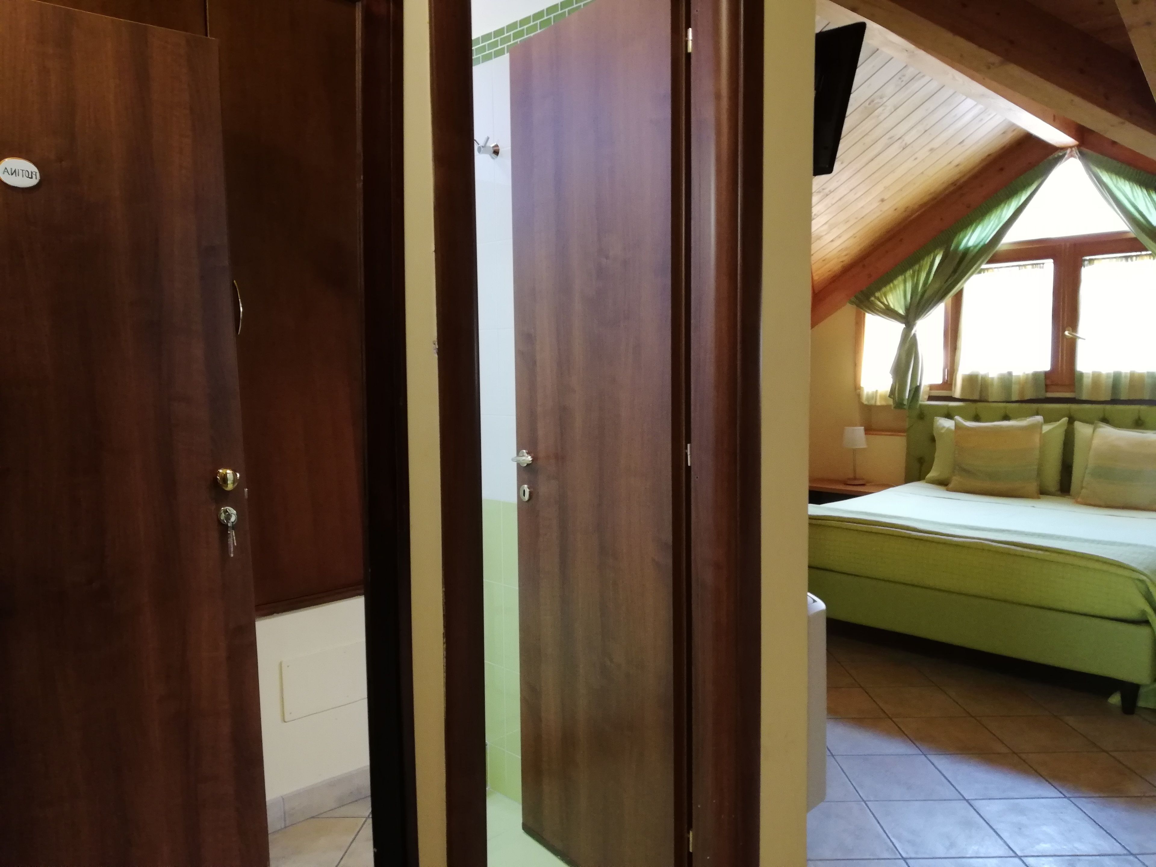 Un dormitorio con cama, ventana con cortinas y techo de madera.