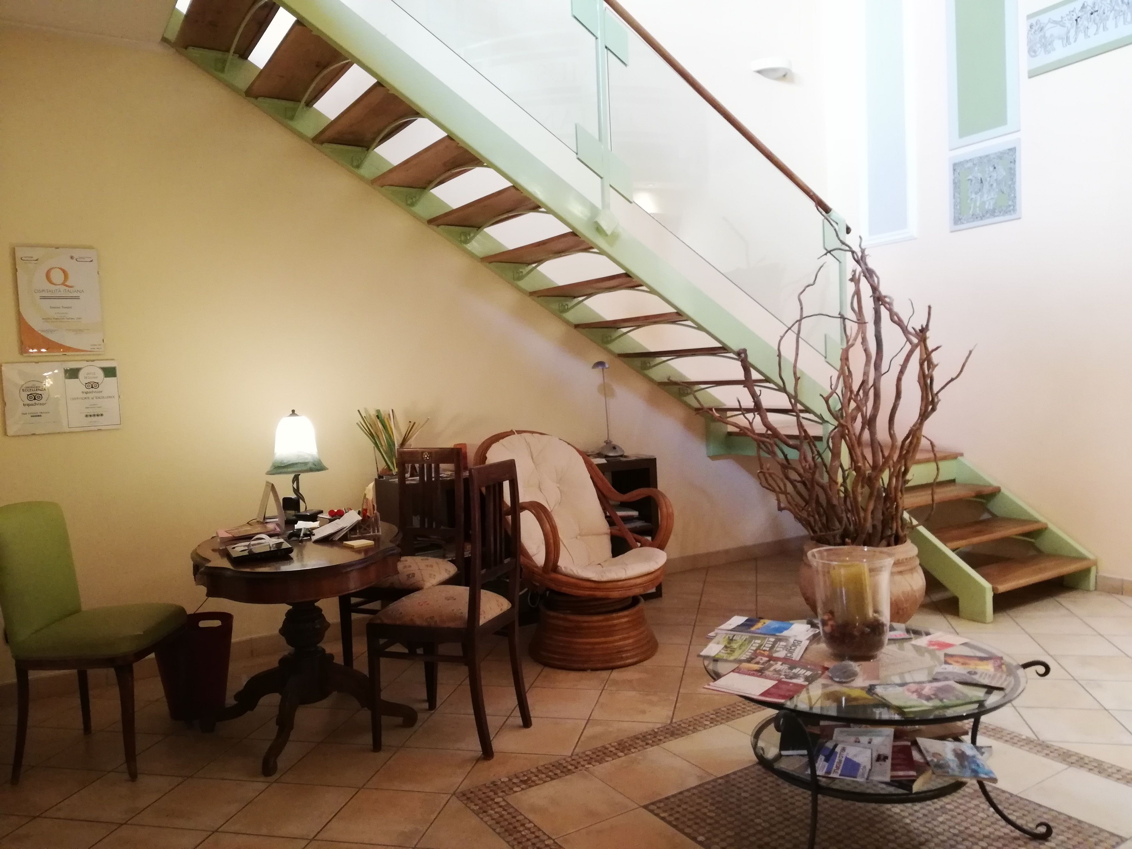 A living room with a staircase, a round table with magazines, a lamp, and a chair.