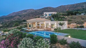 Une villa moderne dotée d’une piscine, d’un espace extérieur aménagé et offrant une vue sur les collines environnantes.