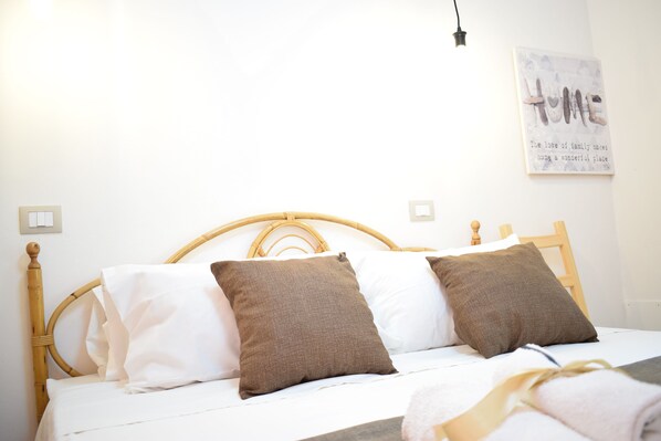 A bed with a wooden headboard, white and brown pillows, and a wall-mounted light fixture.