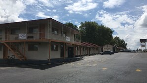 Un motel con un edificio de dos pisos, un área de estacionamiento techada y un cartel que indica WiFi gratuito.