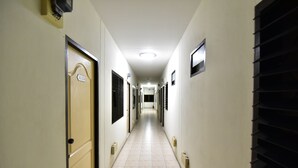 A long, narrow hallway with doors on both sides, each marked with a number. - Kaesai Place (Pattaya)