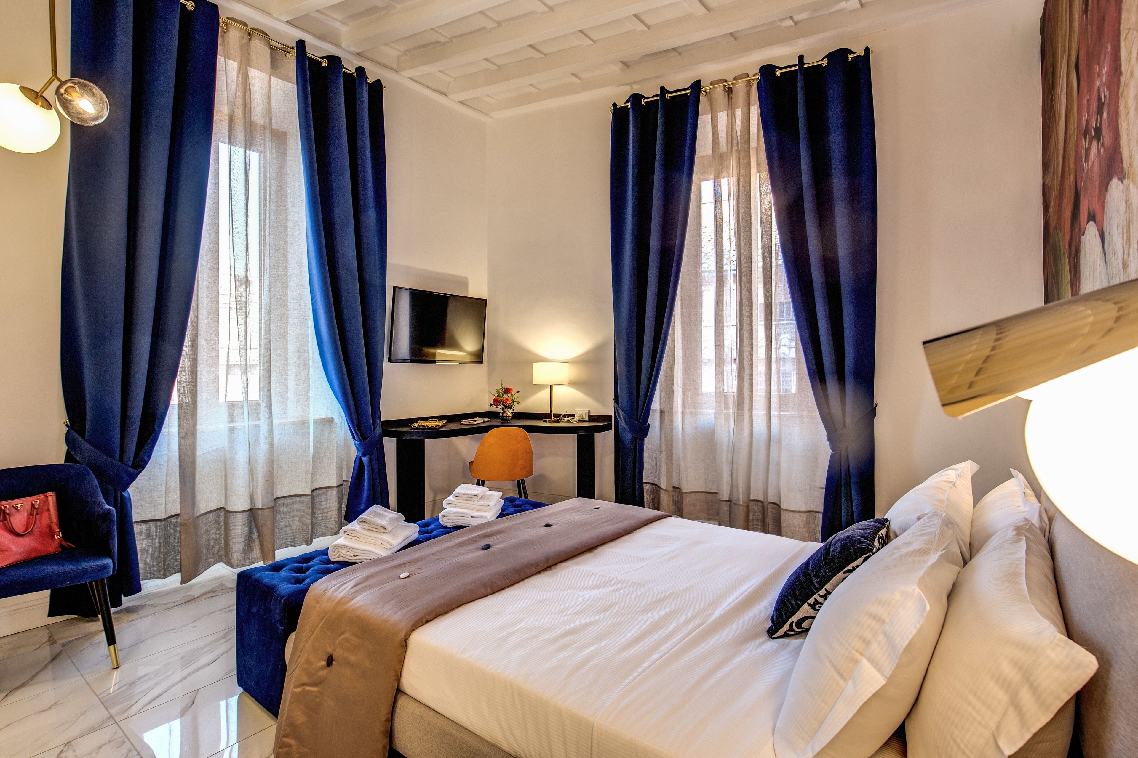 A hotel room with a bed, a desk, a chair, and a TV.