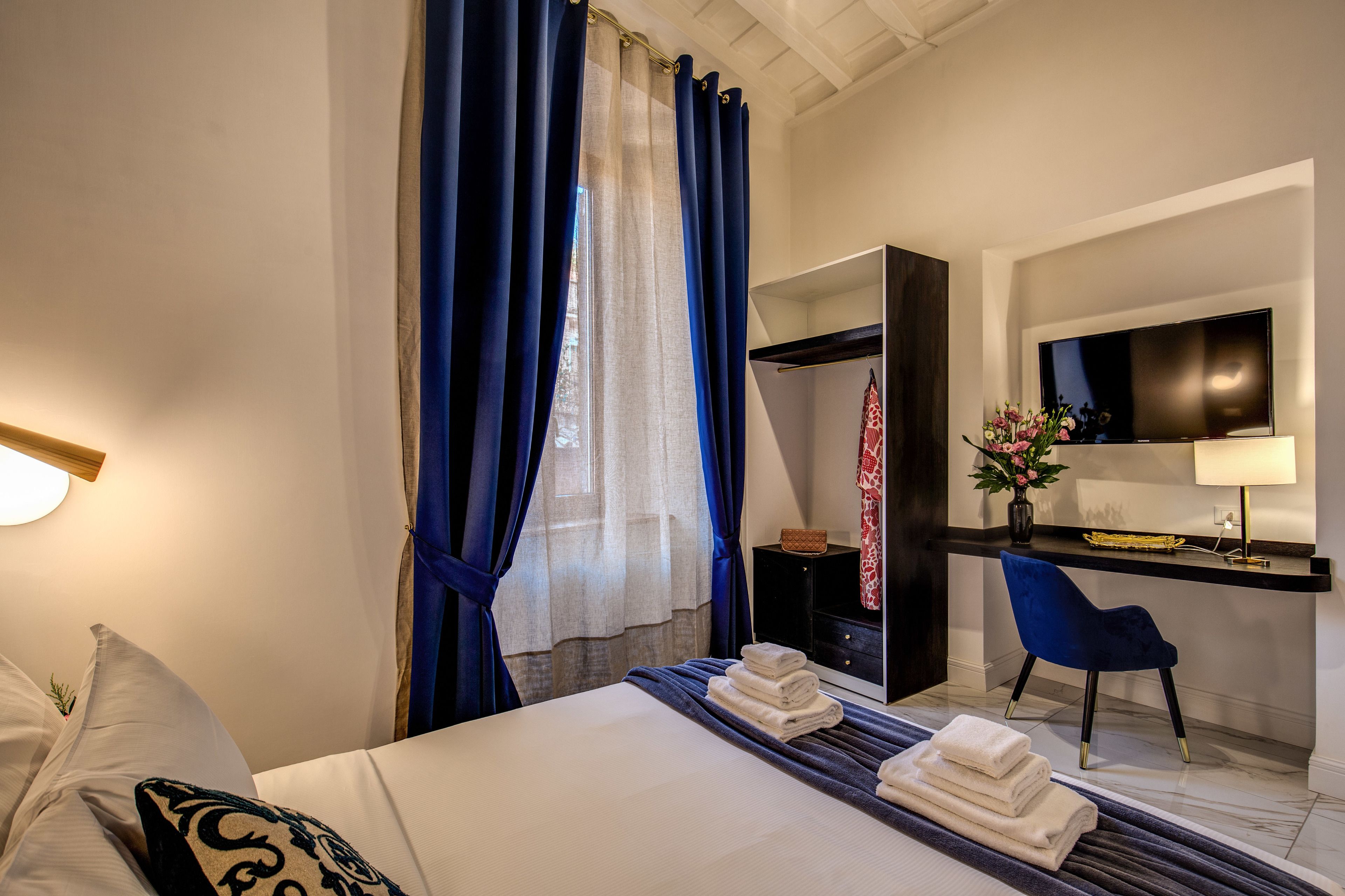 A hotel room with a bed, a desk, a chair, and a TV.