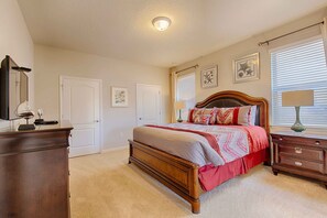 Een slaapkamer met een houten bed, een dressoir, een nachtkastje en een raam met jaloezieën.