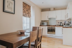 Kitchen equipped with oven, microwave, coffee maker, kettle, and toaster.
