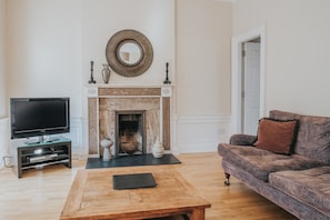 A living room with a fireplace, a television, and a sofa. - Reizand Apartments, Young St (Edinburgh)