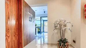 A hallway with a wooden door, a potted orchid, and a fire extinguisher on the wall. - Bel Residence (Split)