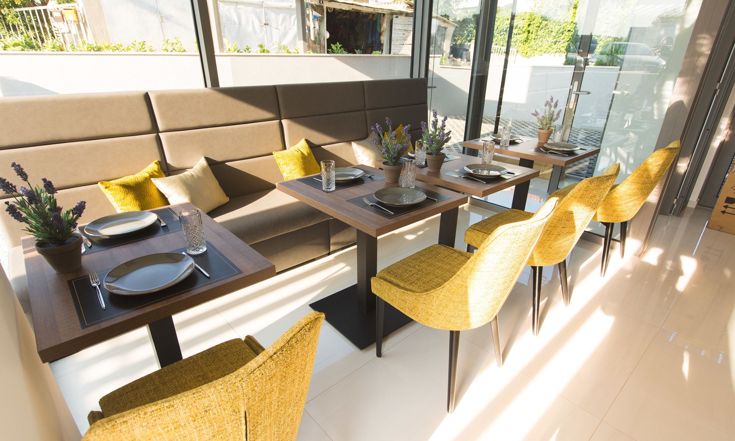 A modern dining area with high tables, cushioned seating, and potted plants.