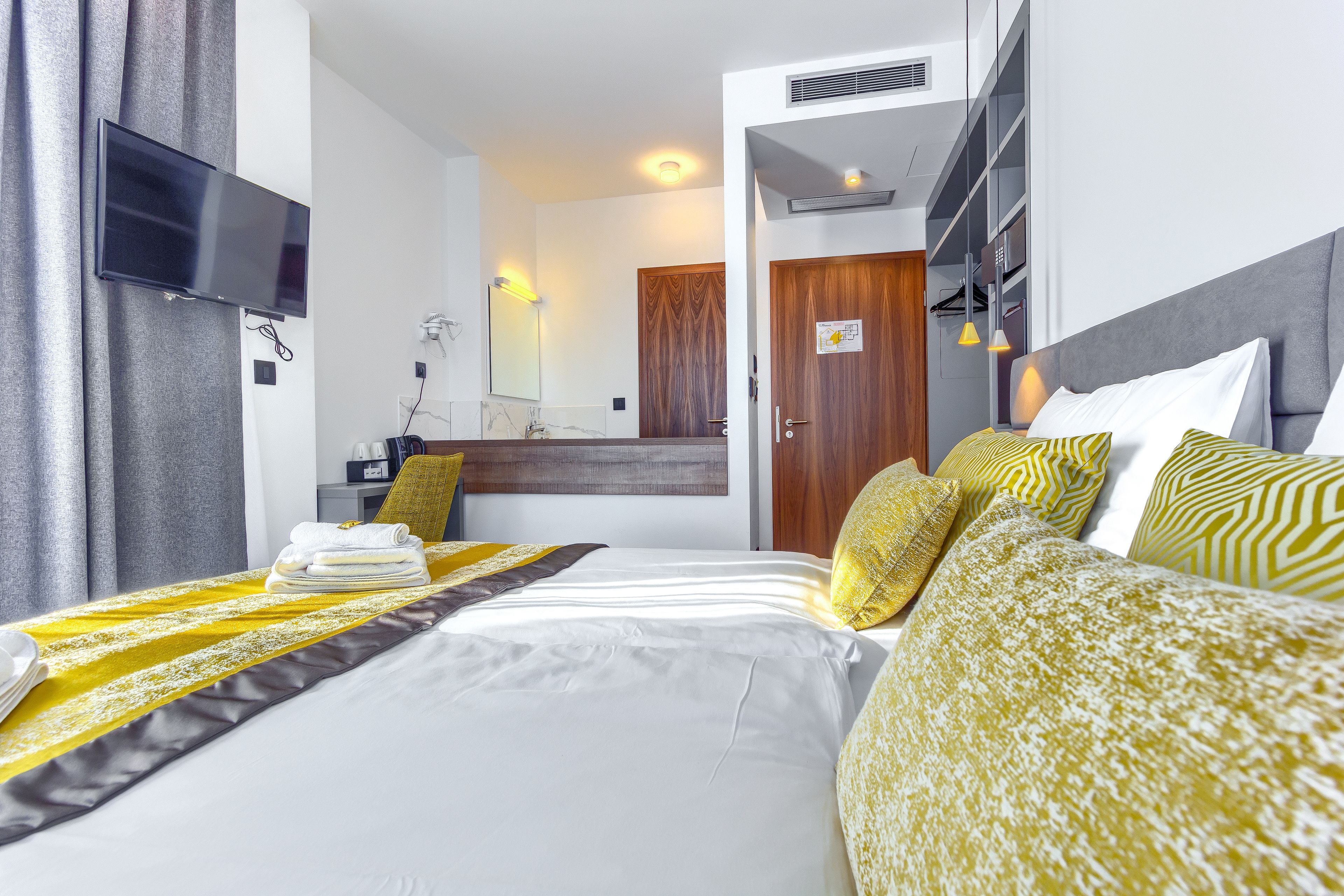 Ein Hotelzimmer mit Bett, Fernseher, Badezimmer und Kleiderschrank.