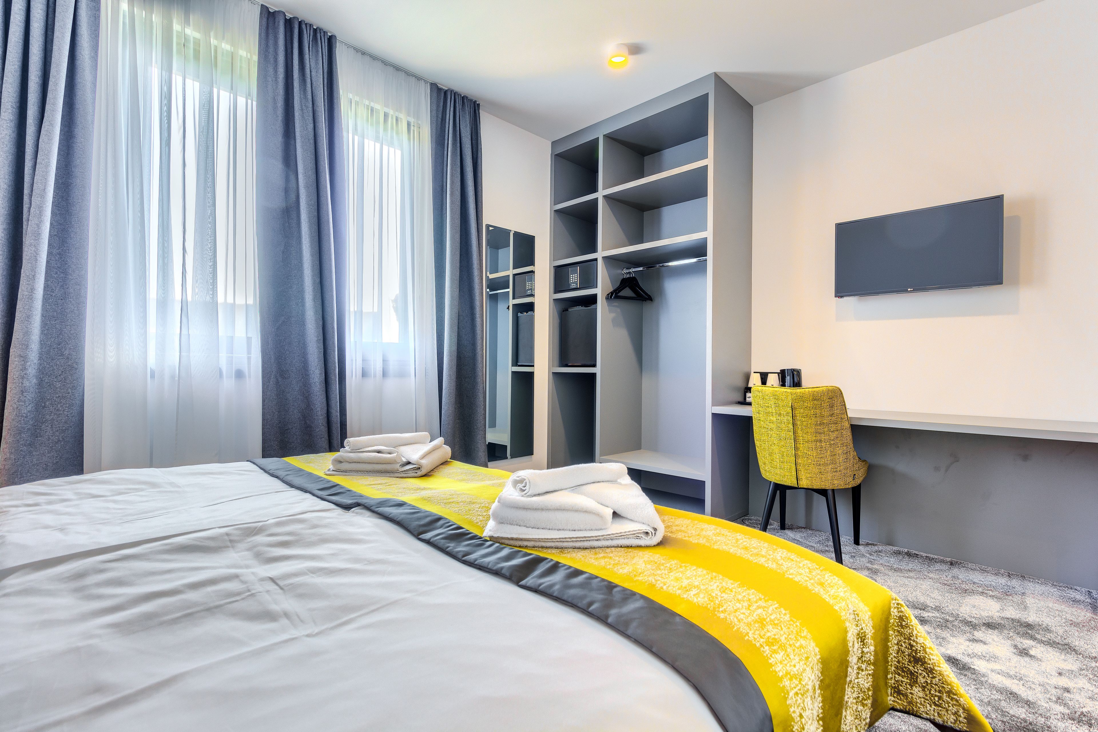 A hotel room with a large bed, a wardrobe, a desk, and a chair.