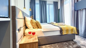 A modern hotel room with a large bed, a bedside table with two glasses of red wine, and a flat-screen TV mounted on the wall. - Bel Residence (Split)