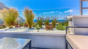 A terrace with a view of the sea, featuring a table and chairs, and various plants. - Bel Residence (Split)