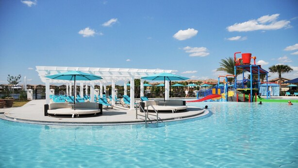 A swimming pool with lounge chairs and umbrellas, a water slide, and a play structure. - Shv1206ha - 8 Bedroom Villa In Windsor At Westside, Sleeps Up To 18, Just 7 Miles To Disney (Kissimmee)