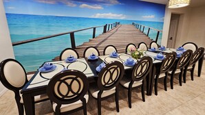 A dining area with a view of the ocean through a mural, a wooden deck, and a table set for eight with blue tableware. - Shv1206ha - 8 Bedroom Villa In Windsor At Westside, Sleeps Up To 18, Just 7 Miles To Disney (Kissimmee)