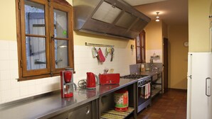 A kitchen with a stainless steel countertop, a stove, a sink, and a refrigerator. - Maison de Veaux (Malaucène)