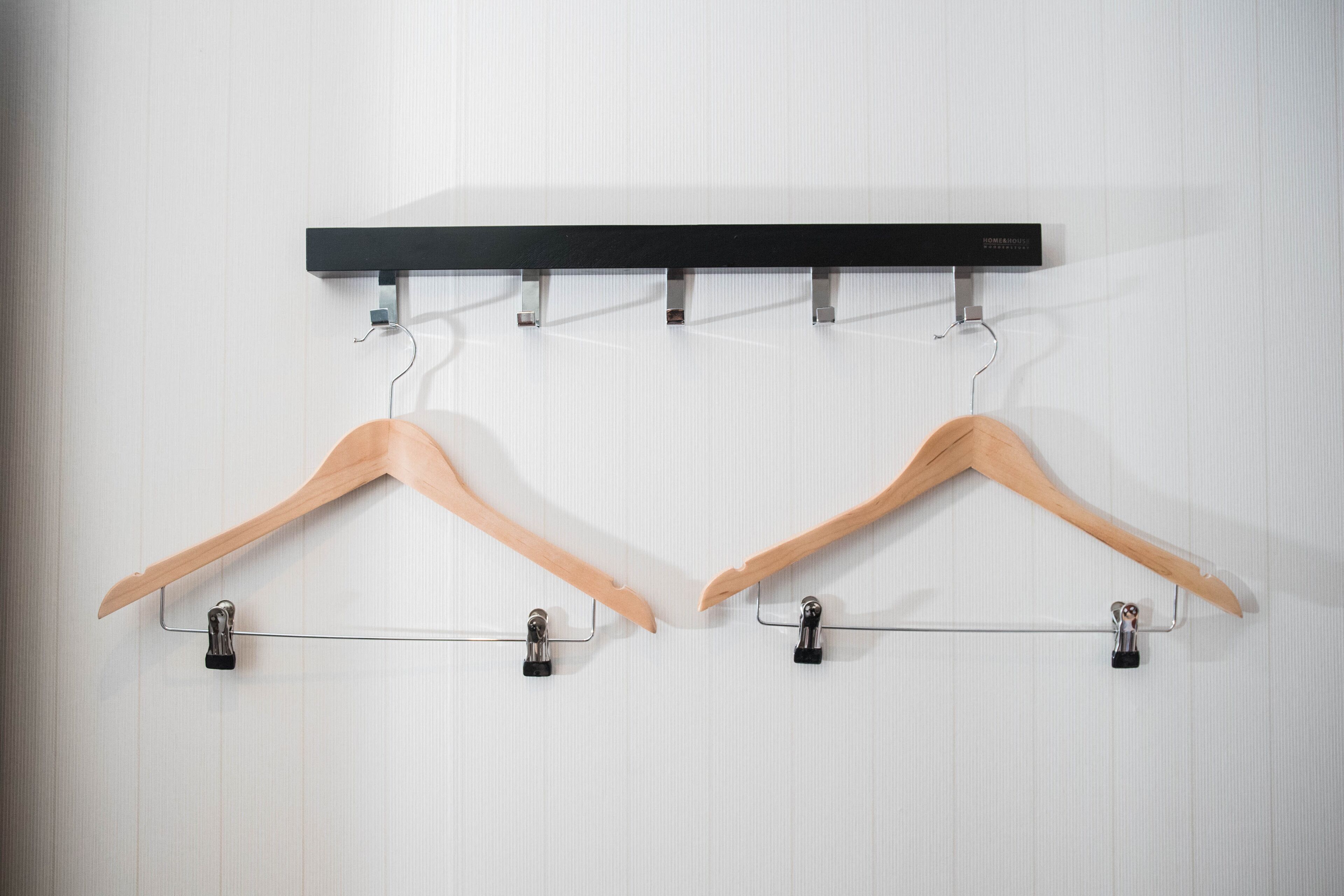 Two wooden hangers mounted on a wall with a black horizontal bar above them.