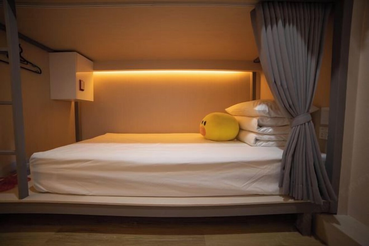 A bunk bed with a headboard, a bedside lamp, and a plush toy on the bed.