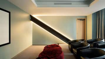 A modern room with a sloped ceiling, a projector screen, and a seating area with black chairs.
