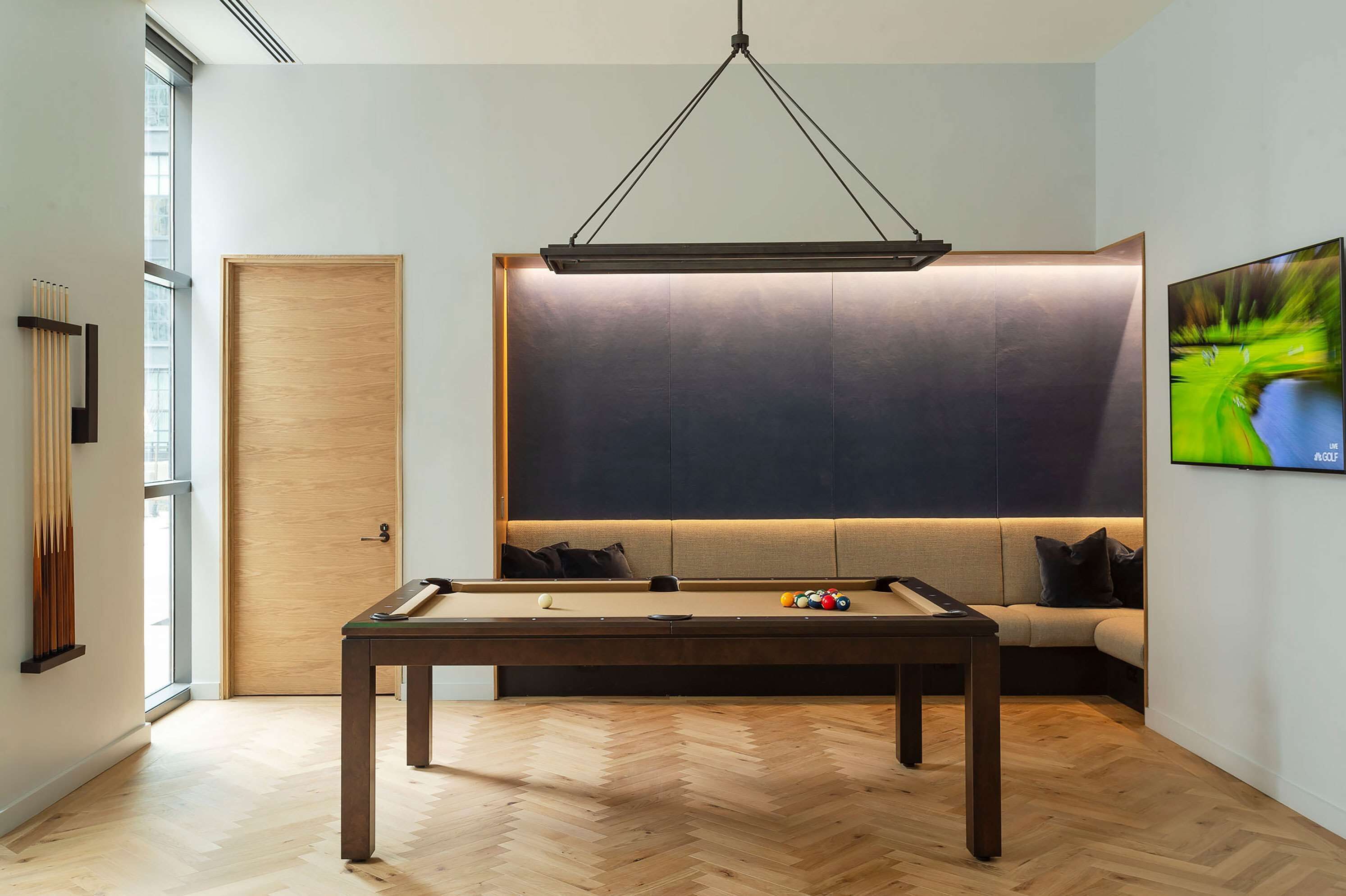 A pool table in a room with a large window, a sofa, and a television.