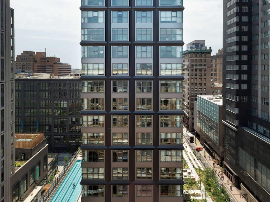 A high-rise building with a modern design, featuring a rooftop pool and surrounding greenery.