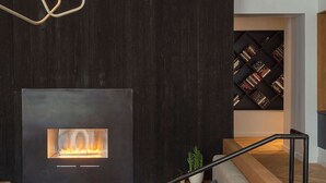Ein modernes Wohnzimmer mit Kamin, Sofa, Couchtisch und Bücherregal.