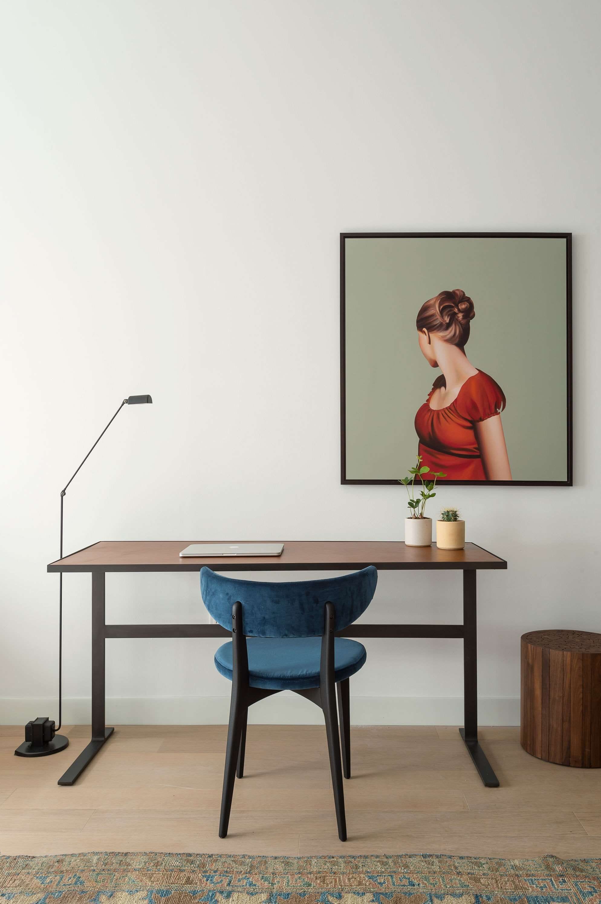 Ein moderner Arbeitsplatz mit Schreibtisch, Stuhl, Lampe und gerahmten Bildern.