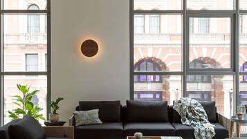 A modern living room with a sofa, coffee table, and a large window with a view of a building.