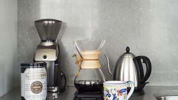 Eine Kaffeemaschine, eine Glas-Kaffeekanne, ein Kaffeekännchen und eine Tasse auf einer Küchenarbeitsplatte.