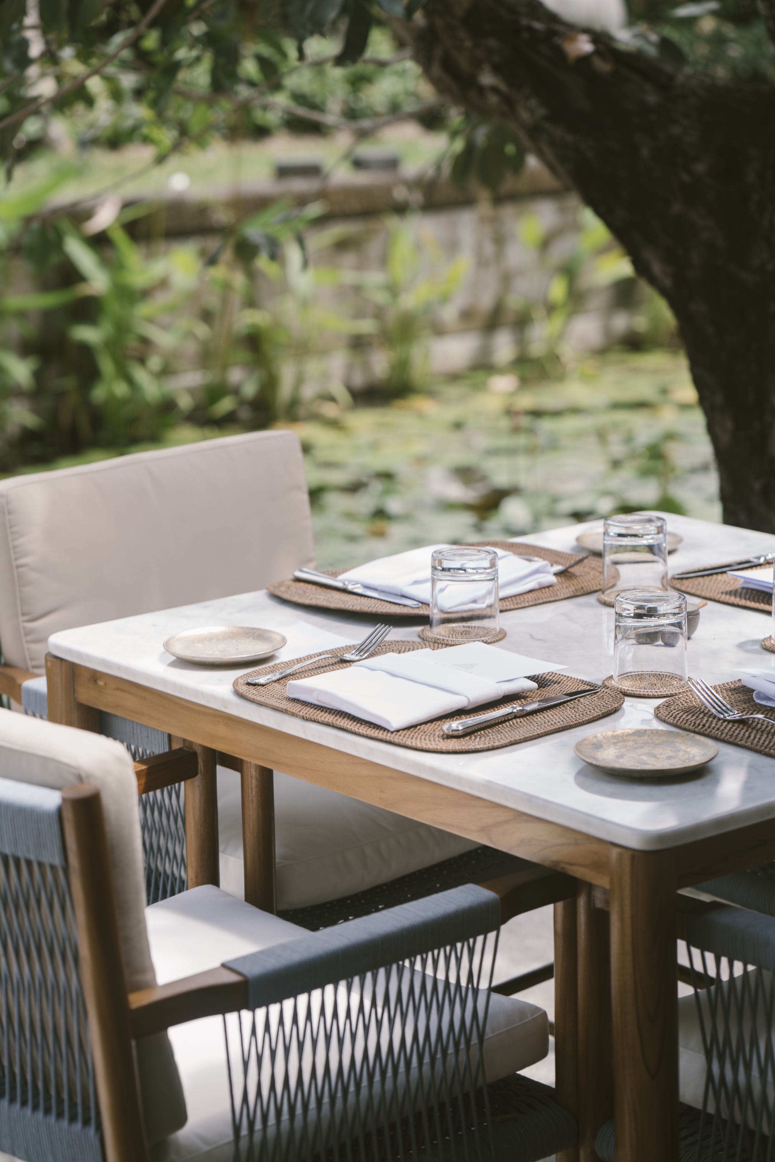 An outdoor dining area with a table set for two, surrounded by cushioned chairs.