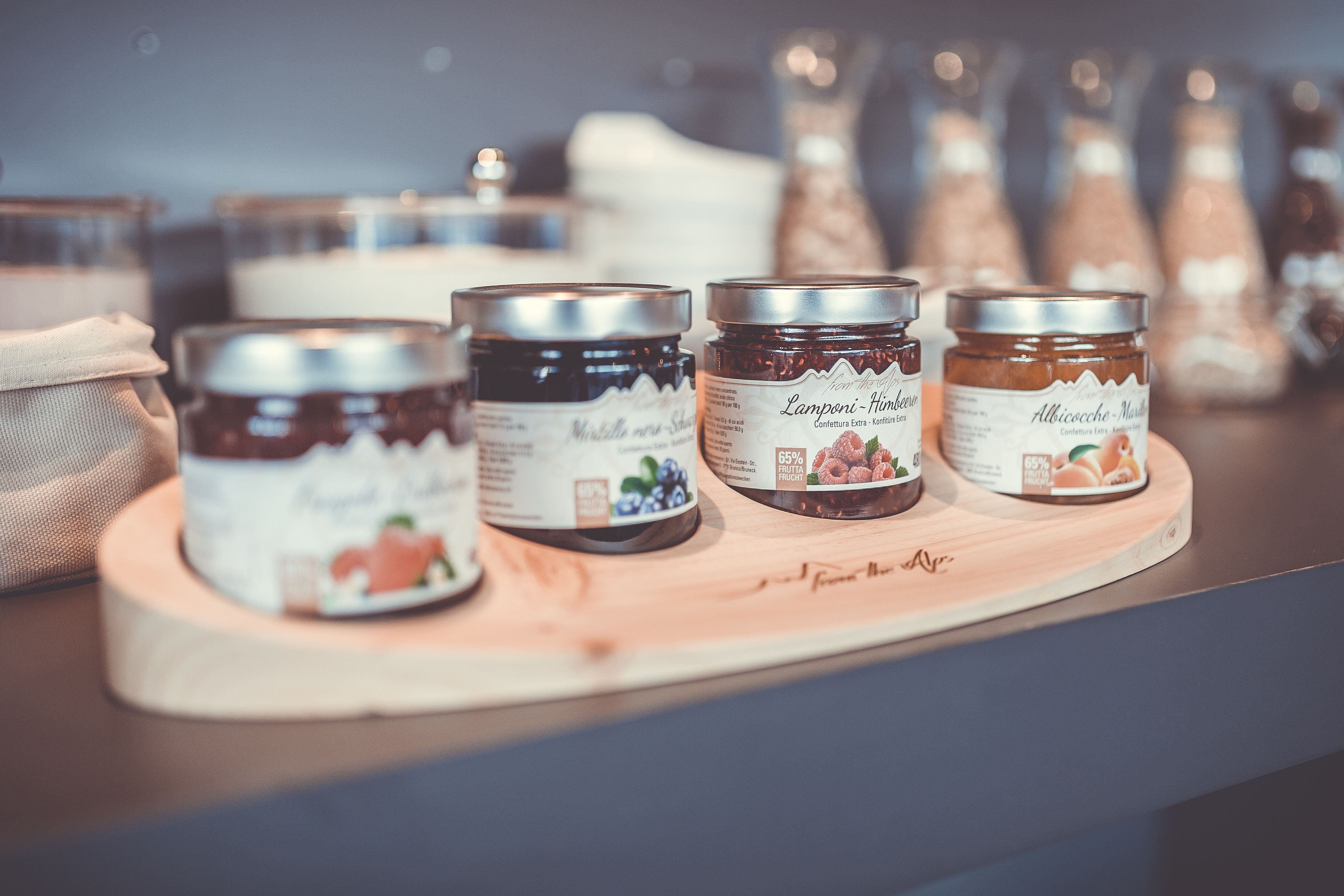 Four jars of jam on a wooden board.
