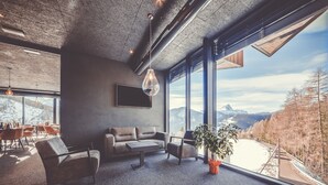 A modern living room with a large window overlooking a snowy mountain landscape.