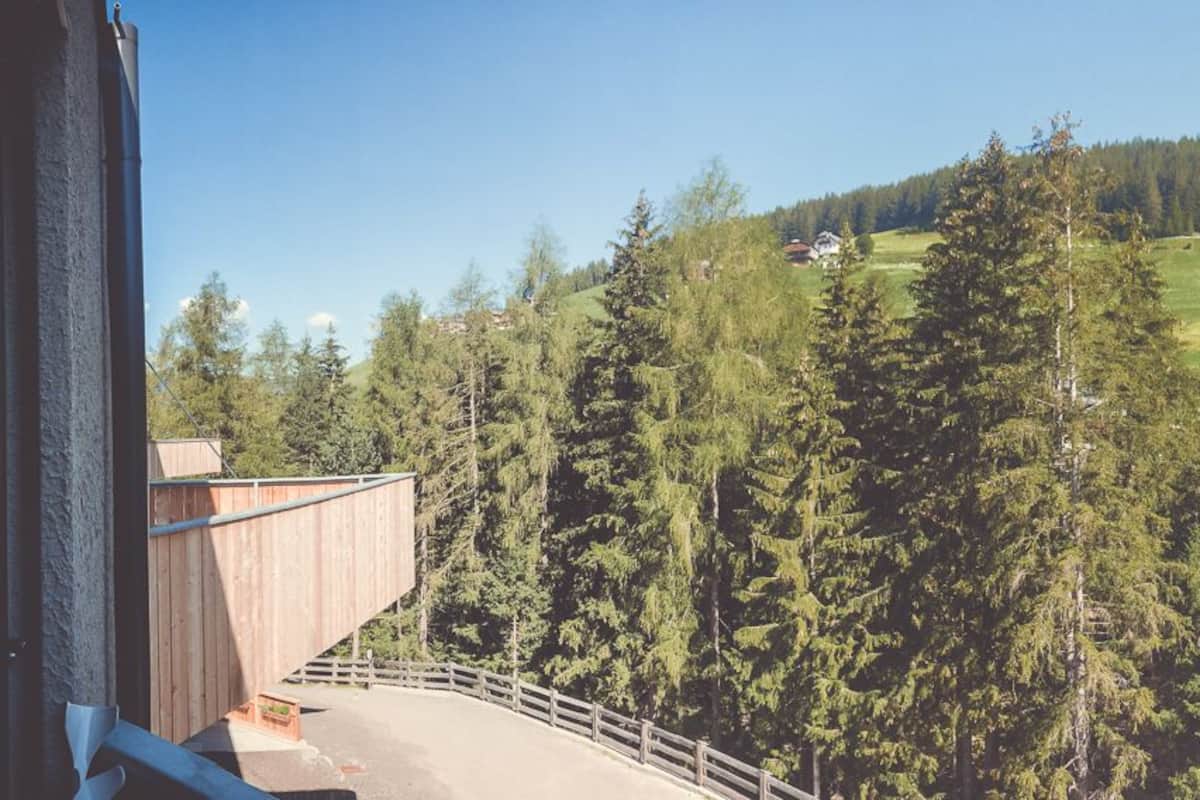A panoramic view of a mountainous landscape with a wooden deck and a clear sky.