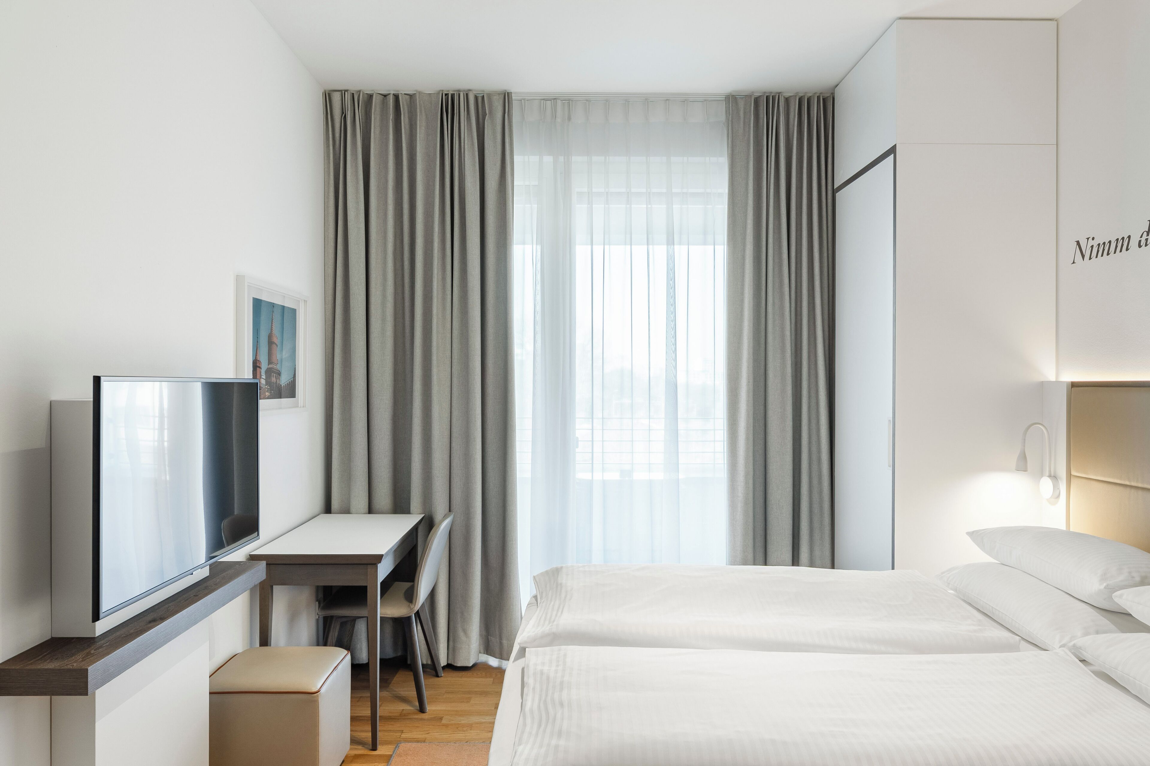 Una habitación de hotel con una cama, un escritorio, una silla y un televisor.