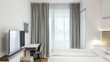 Una habitación de hotel con una cama, un escritorio, una silla y un televisor.