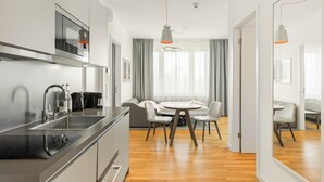 Une cuisine moderne équipée d’une cuisinière intégrée, d’un évier et d’un four à micro-ondes. On y trouve également un coin repas avec une table ronde et des chaises.
