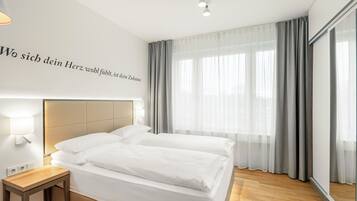 Una habitación de hotel moderna con una cama grande, una mesita de noche y una lámpara fijada a la pared.