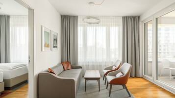 A modern living room with a sofa, chairs, a coffee table, and a large window with curtains.