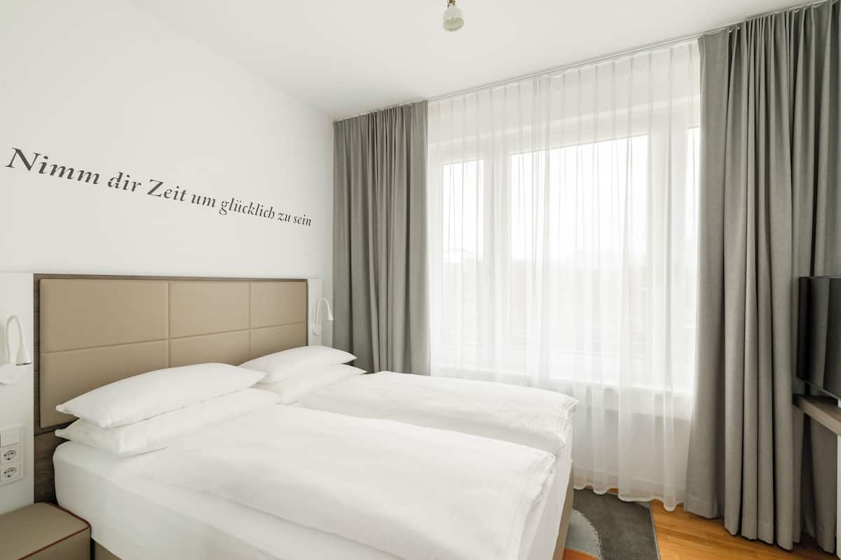 Une chambre d’hôtel avec un lit, une télévision et une fenêtre avec des rideaux.
