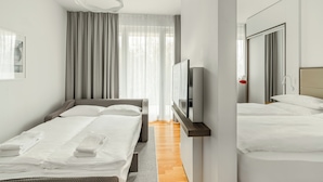 Une chambre d’hôtel moderne avec un grand lit, un plus petit lit, une télévision et un miroir.