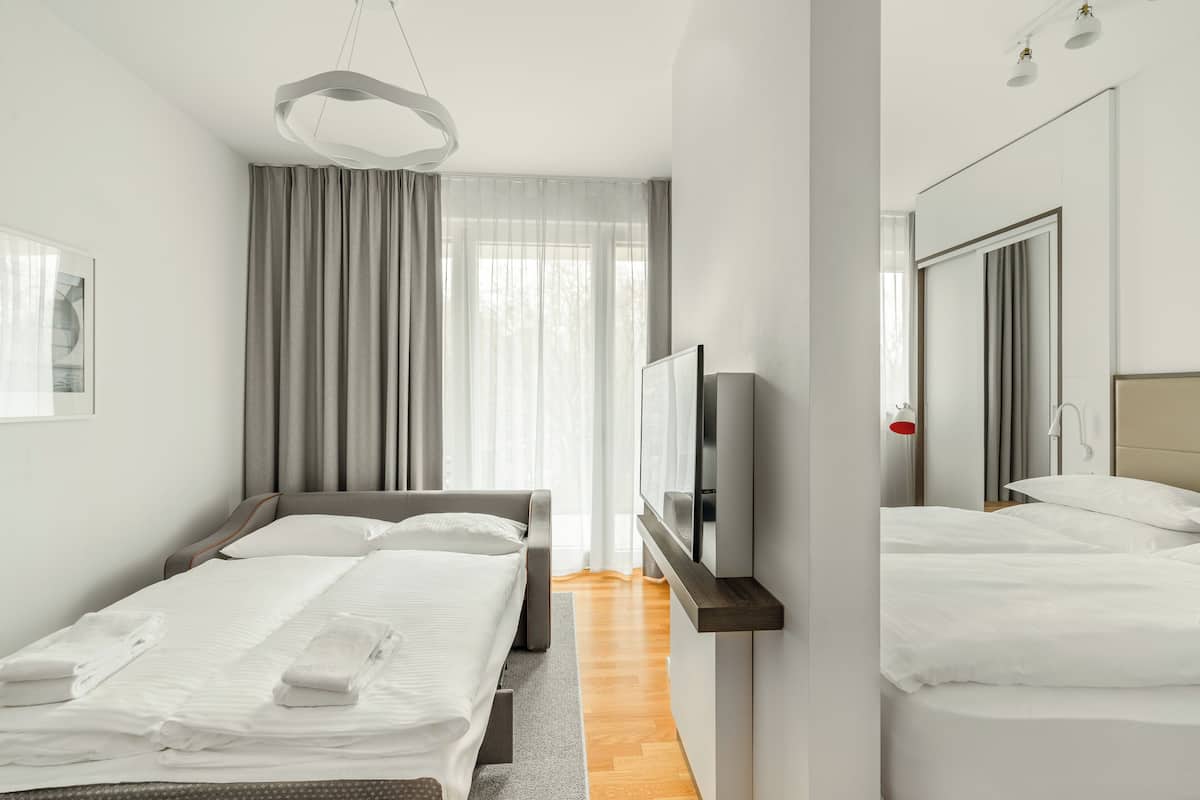 Une chambre d’hôtel moderne avec un grand lit, un plus petit lit, une télévision et un miroir.
