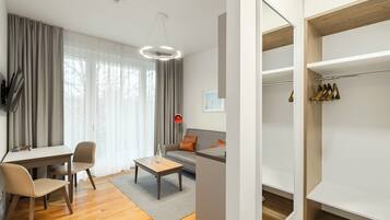 A modern living room with a sofa, coffee table, and chairs. There is a dining area with a table and chairs. The room has large windows with curtains.