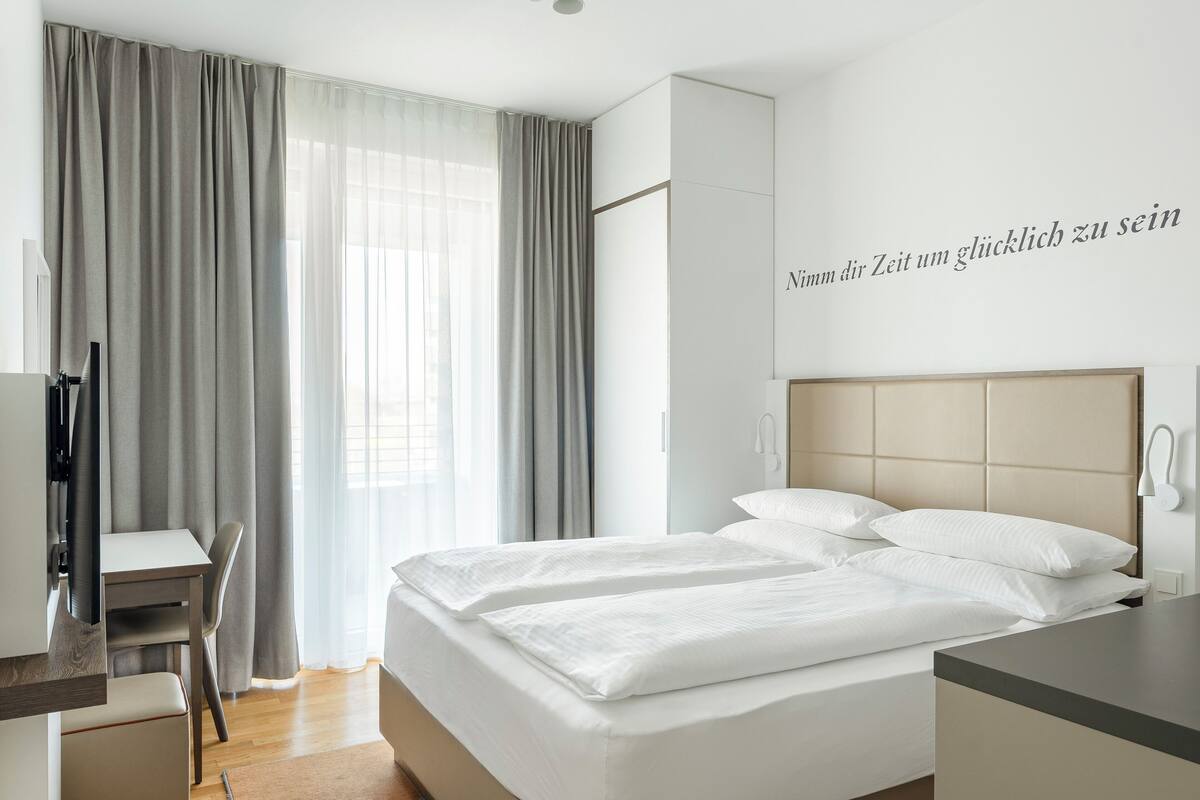 Une chambre d’hôtel avec un lit, un bureau et une chaise.