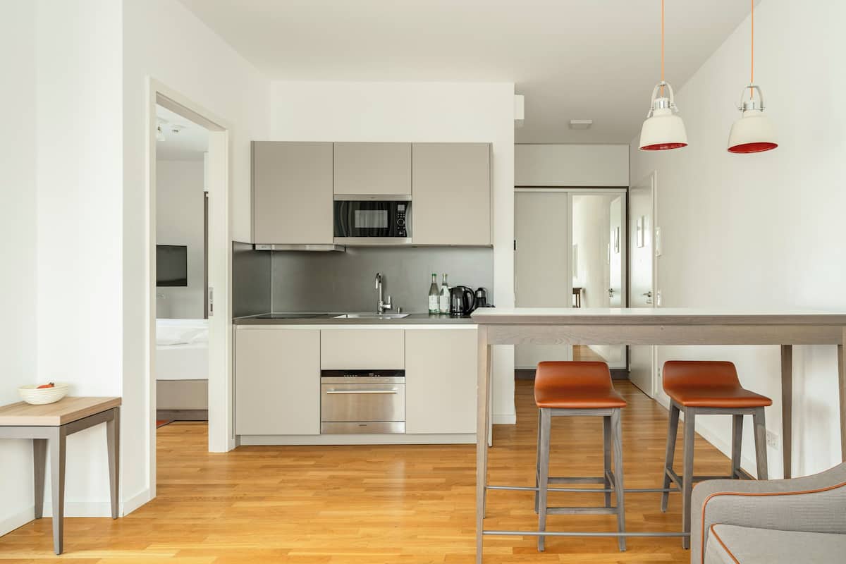 Une cuisine moderne dotée d’un îlot central, d’appareils électroménagers en acier inoxydable et de deux tabourets de bar.