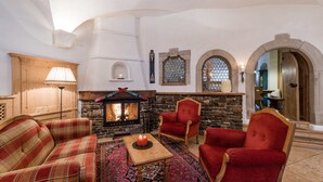 Una habitación acogedora con chimenea, sillas rojas, un sofá de cuadros y una alfombra estampada.