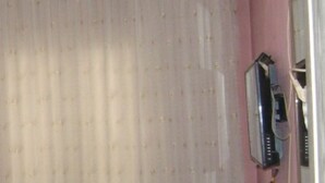 A room with a pink wall, a painting of a landscape, and a white curtain. - Hotel Sungur (Demirci)
