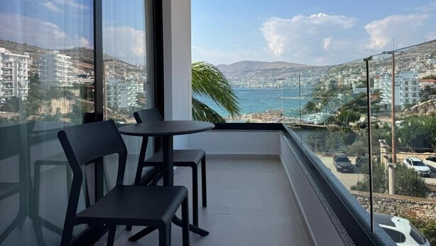 Un balcón con vista a una ciudad costera, una mesa y dos sillas.