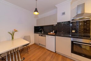 A modern kitchen with white cabinets, a black backsplash, and stainless steel appliances.