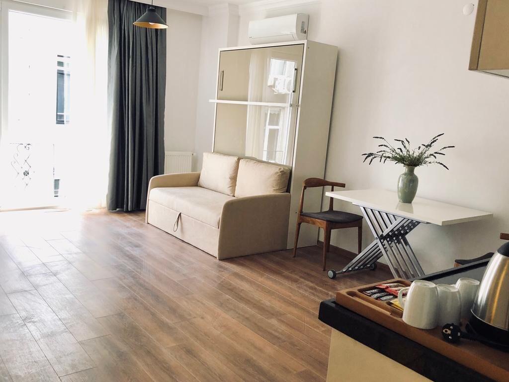 A modern living room with a sofa, a chair, a small table with a plant, and a radiator.